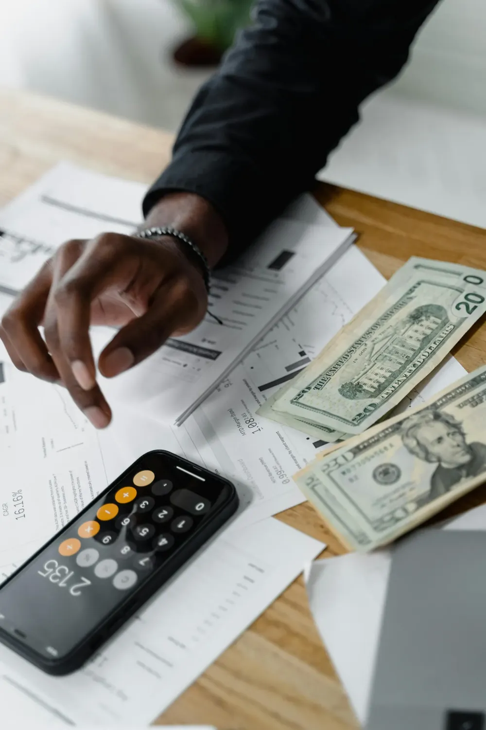 Hands using a calculator with documents and a notepad nearby.